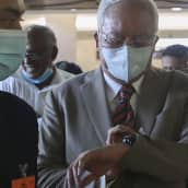Najib Razak katsoo rannekelloaan maski kasvoillaan