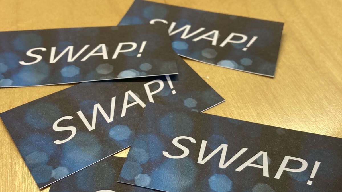 Pöydällä muutama tumma kortti, joissa lukee teksti Swap!