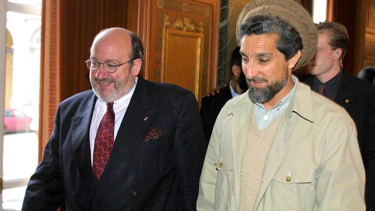 Louis Michel ja Ahmad Shah Massoud kävelevät yhdessä. Michelillä on tumma puku, Massoudille perinteinen afganistanilainen asu ja päähine. Molemmilla on parta.