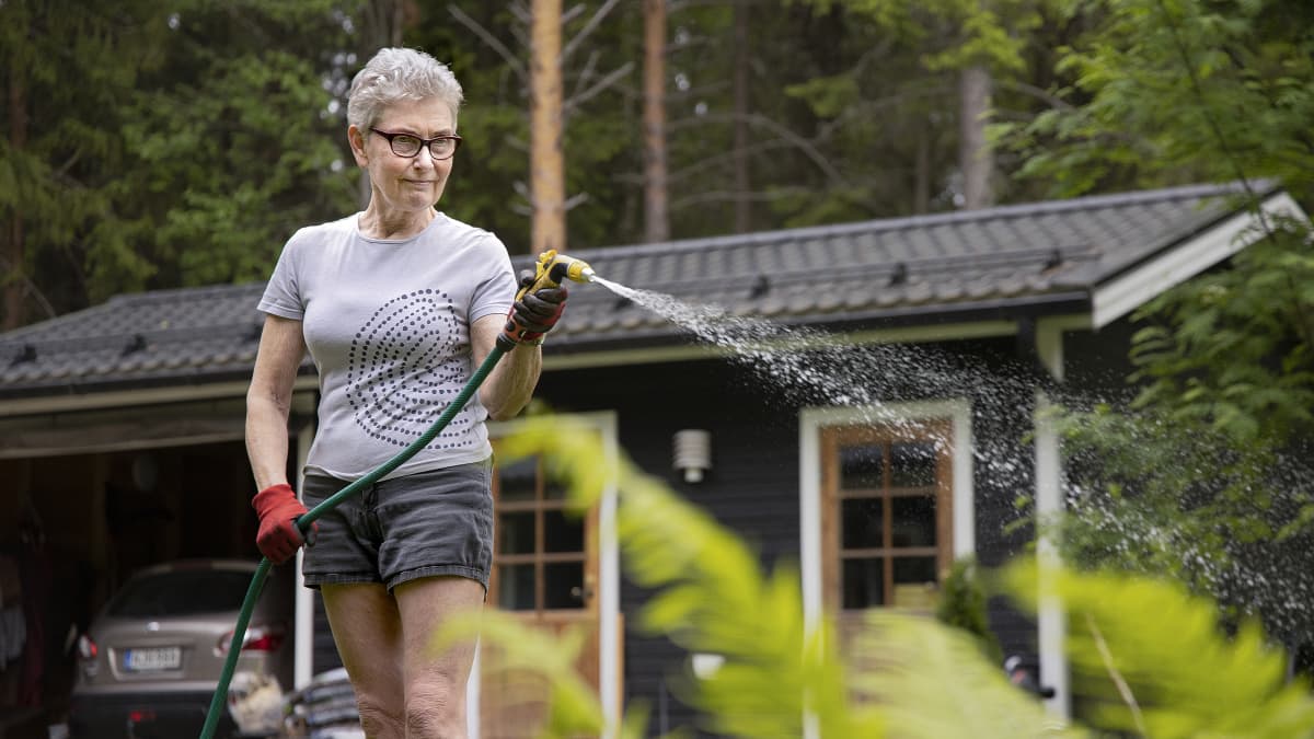 Pirjo-Leena Pitkänen kastelee kukkia.