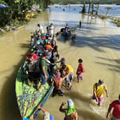 Ihmisiä ja vene tulvavedessä
