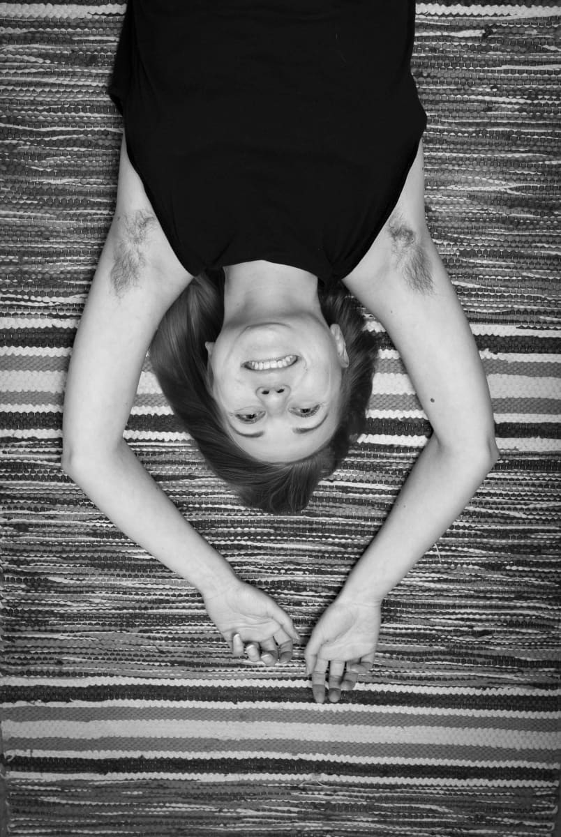 Kati Ojala makaa lattialla räsymatolla kädet ylöspäin ojennettuina.