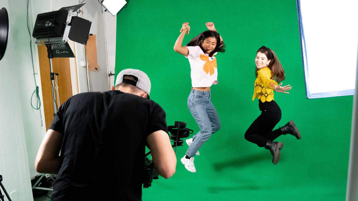 Kaksi naista hyppäämässä ilmaan kameran edessä studiossa.