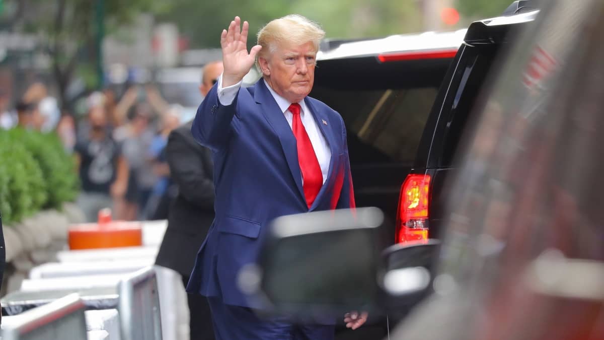 Donald Trump heiluttaa kättään auton vieressä 