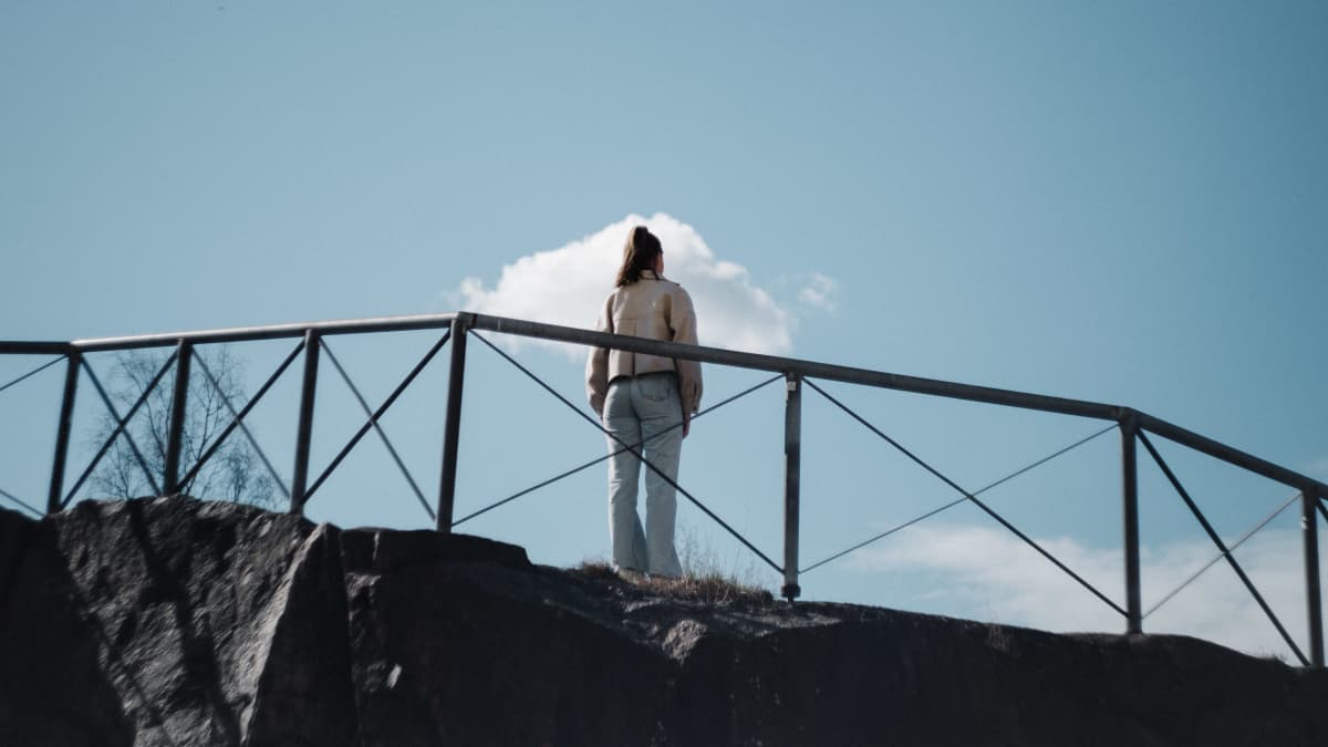 Tyttö seisoo kalliolla.