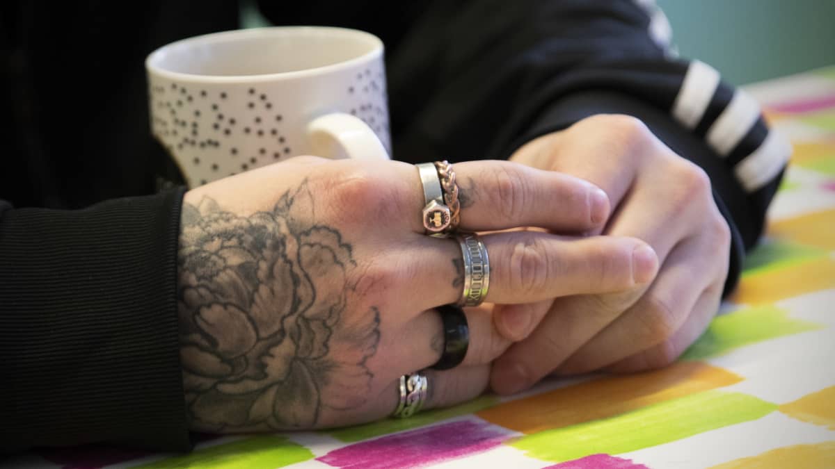 Tatuoidut kädet, joissa paljon sormuksia.