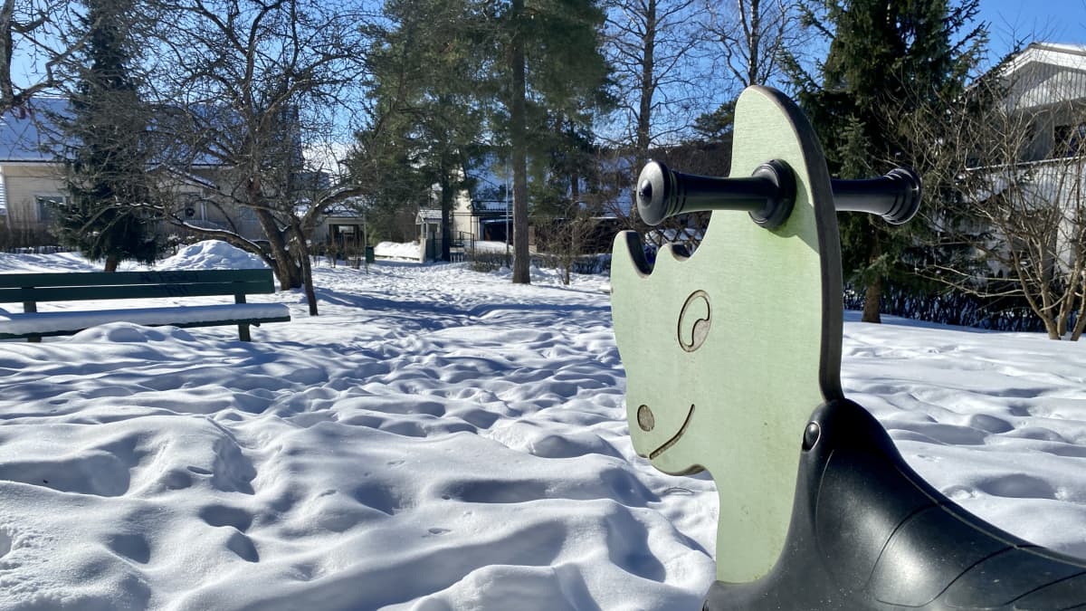 Lumisessa leikkipuistossa on vaaleanvihreä sarvikuonokeinu.