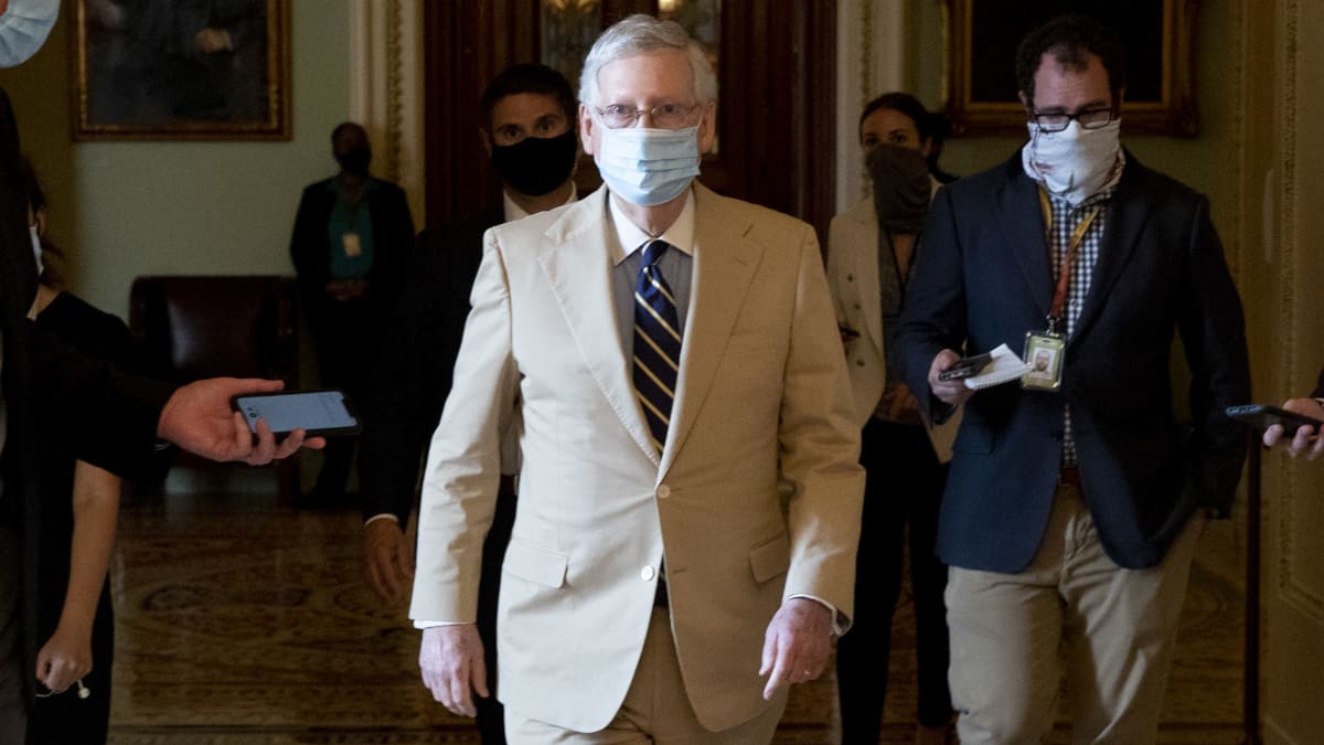 Vaaleaan pukuun pukeutunut senaatin republikaanien johtaja Mitch McConnel kävelee toimittajien keskellä Yhdysvaltain kongessissa.