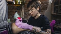 Sopu -tatuointistudion tatuoija Iina Räsänen tatuoi asiakkaan polvea.