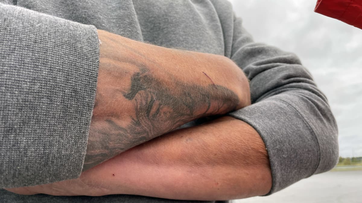 Kädet ristissä, tatuiointi käsivarressa.