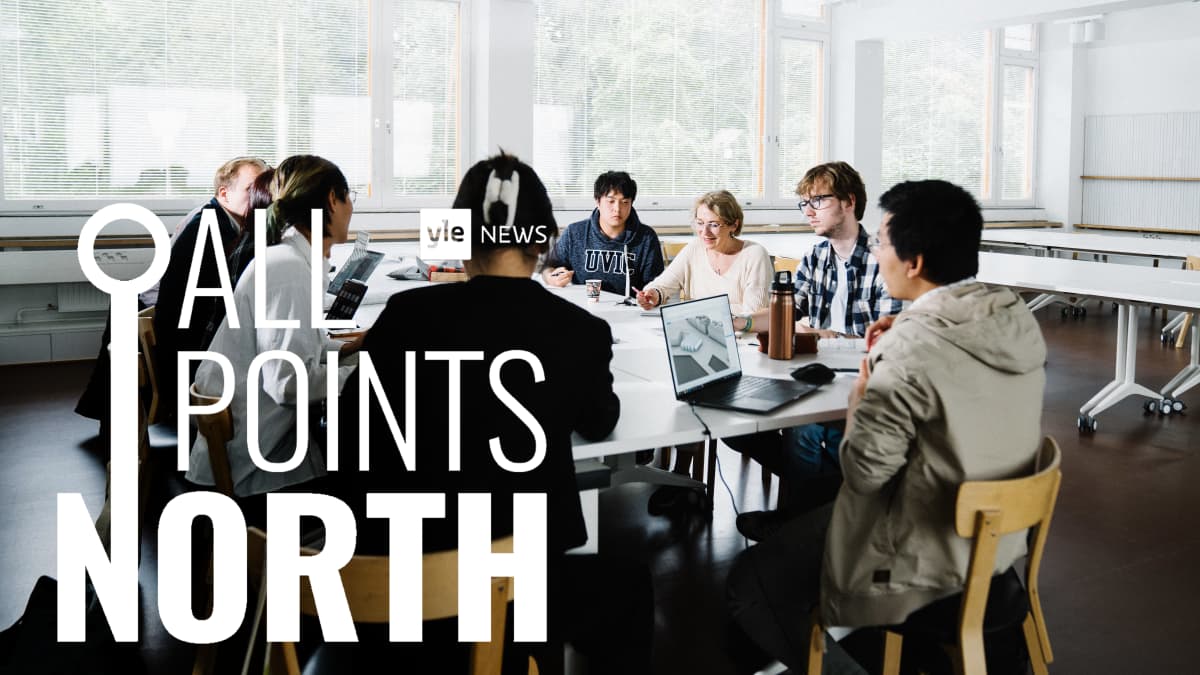 Kuvassa istuu valkoisen pöydän ääressä joukko Aalto-yliopiston arkkitehtuuriopiskelijoita。 Osalla opiskelijoista on kannettavat tietokoneet edessään pöydällä。