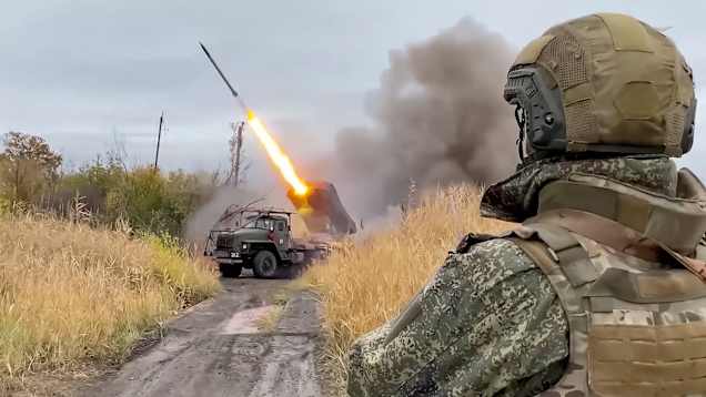 Venäläinen sotilas tarkkailee raketin laukaisua kenttäolosuhteissa syksyisessä maisemassa.