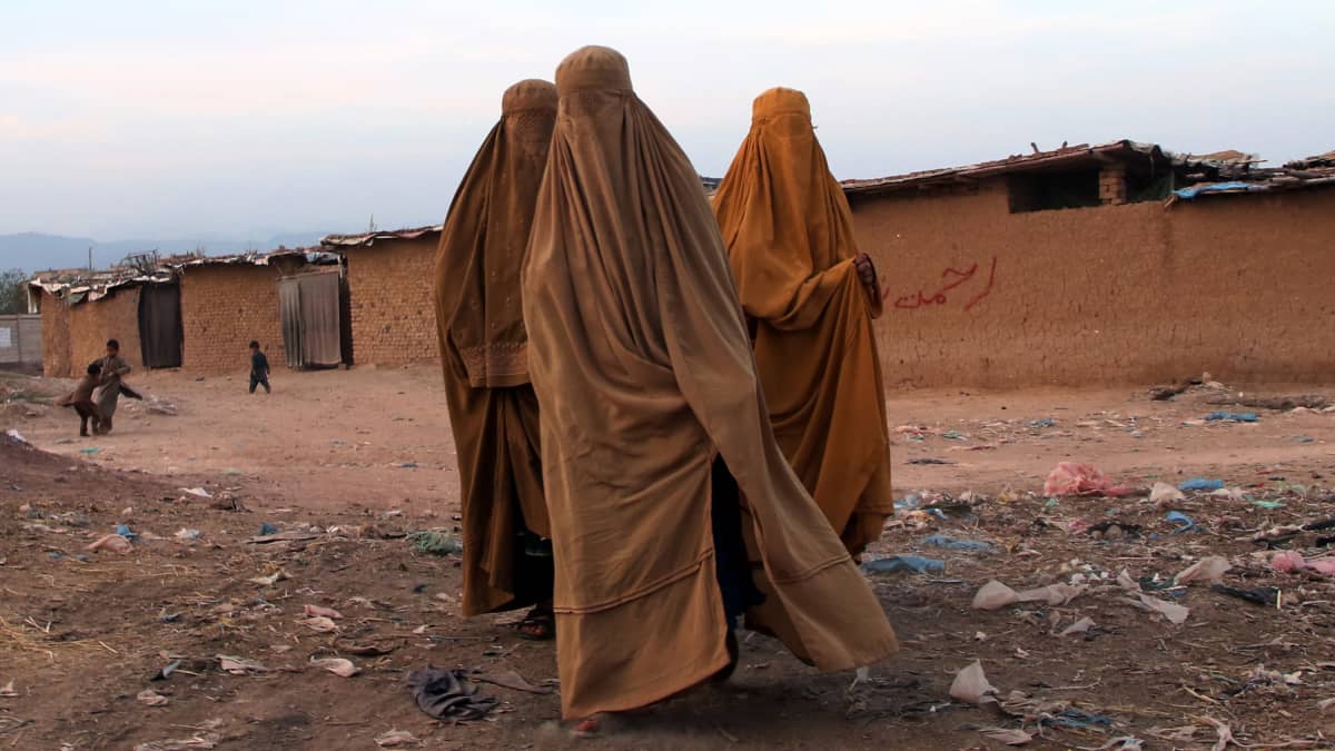 Kolme burkaan pukeutunutta naista pakolaisleirillä Islamabadissa.
