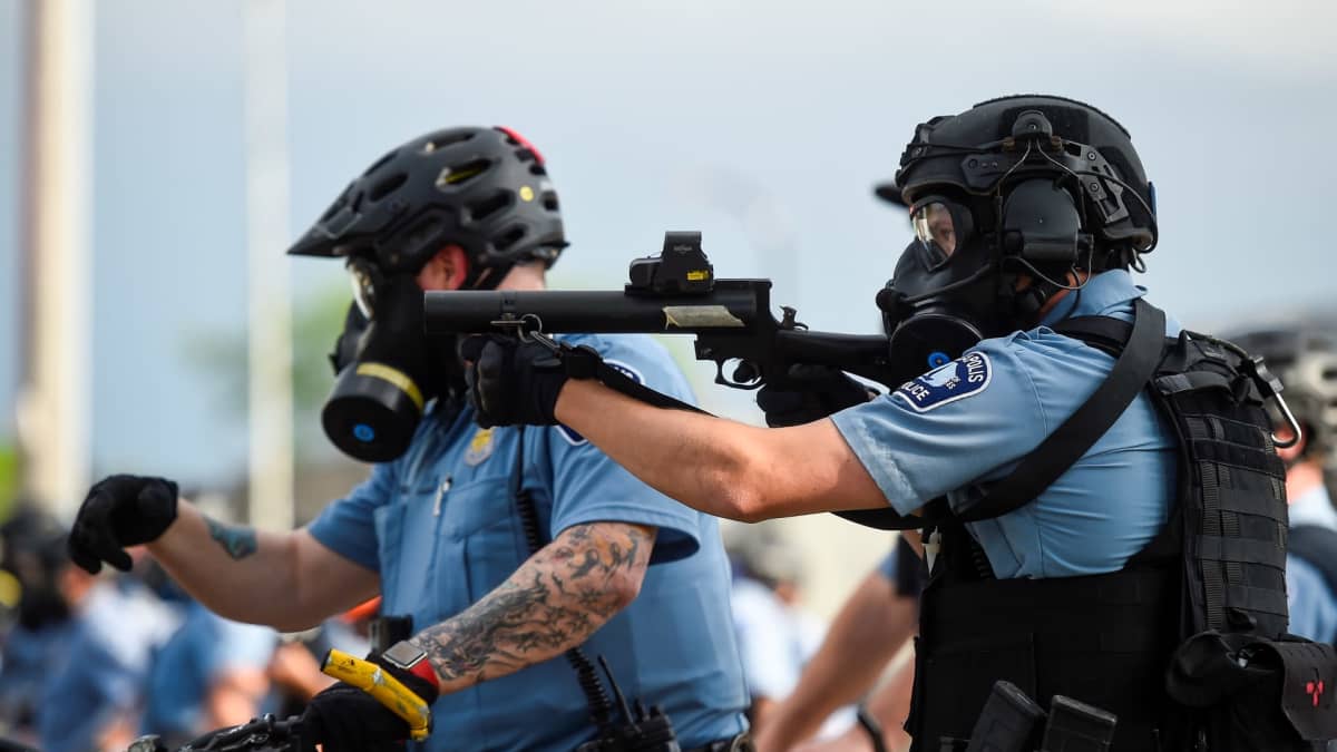 Poliisit tähtäävät aseella mellakoitsijoita Minneapoliksessa, Minnesotan osavaltiossa Yhdysvalloissa.
