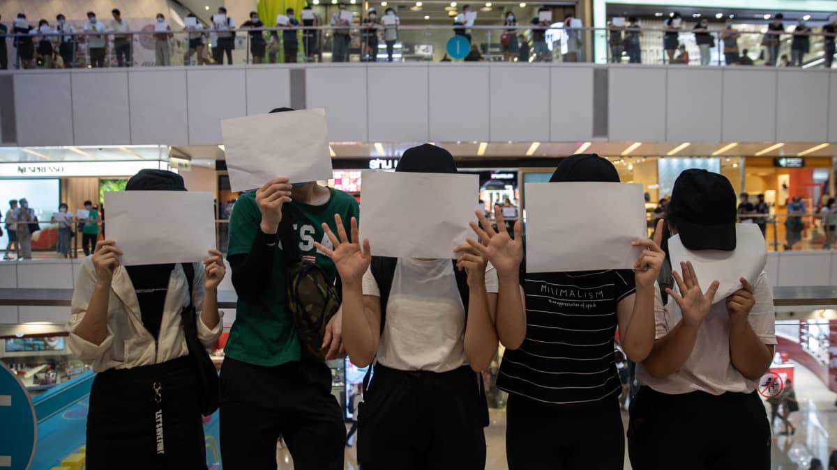 Mielenosoittajia valkoiset paperiarkit kasvojensa edessä