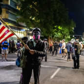 Mielenosoittaja pitää Yhdysvaltain lippua mielenosoitusten keskellä Portlandissa.