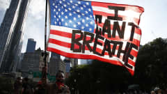 Mielenosoittaja kantaa lippua, jossa lukee "En pysty hengittämään"