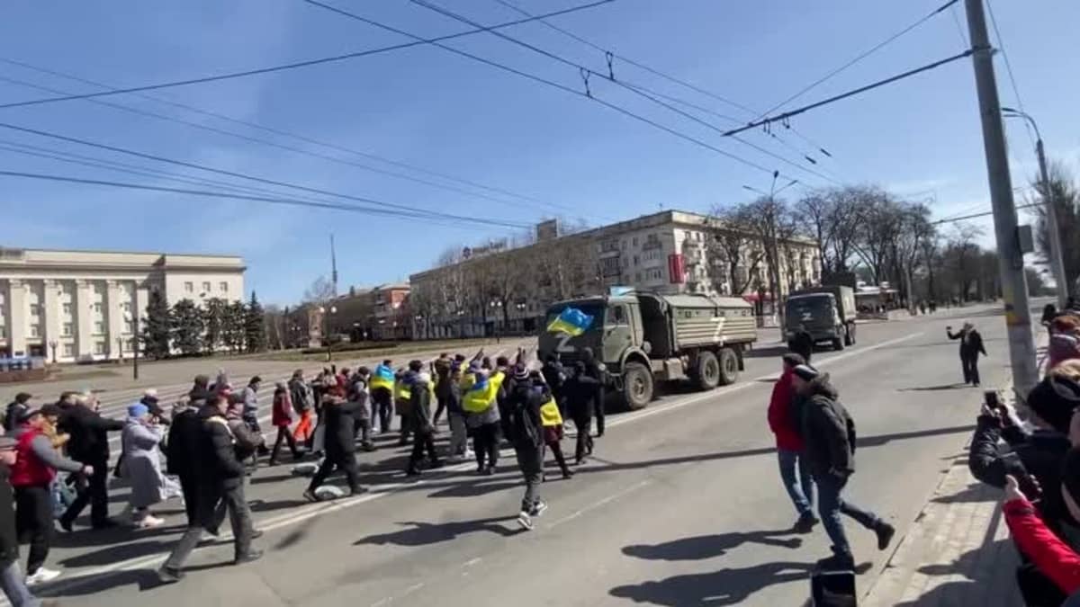 Ukrainalaiset mielenosoittajat huutavat venäläisille joukoille autoissa.