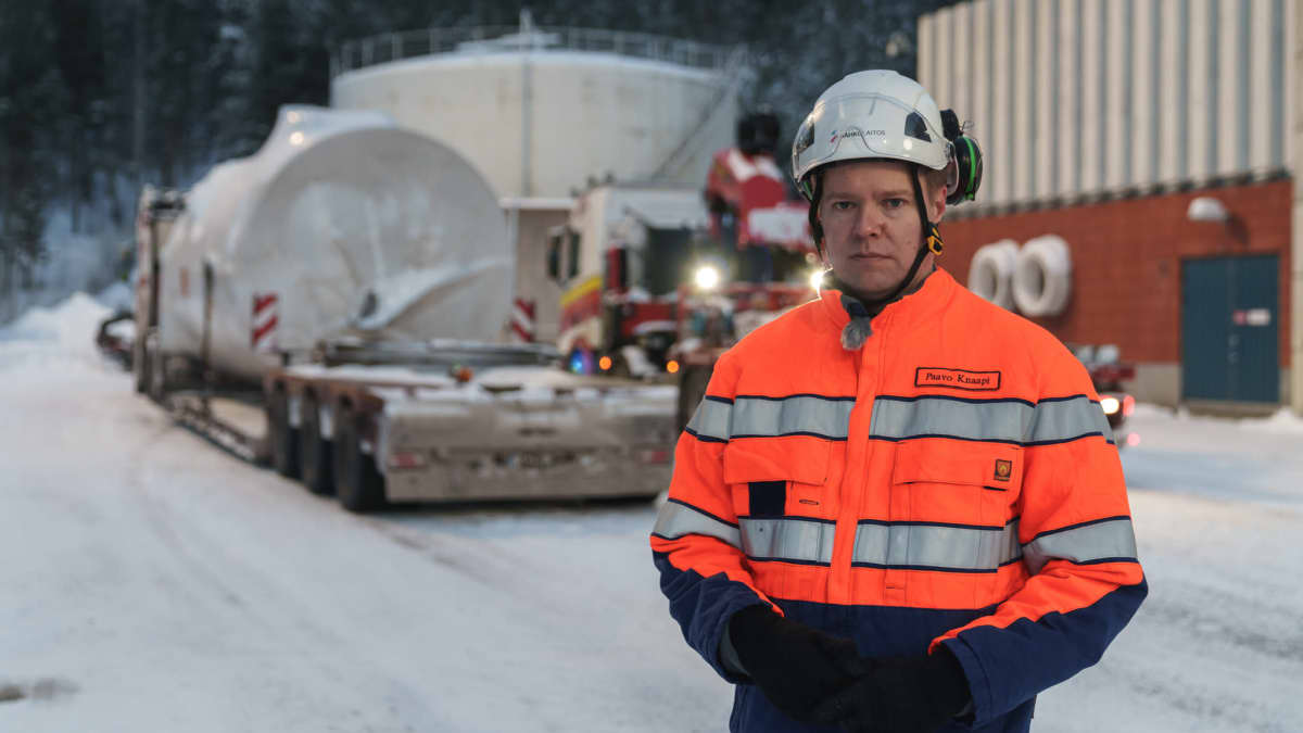 Tampereen sähkölaitoksen Paavo Knaapi seisoo ulkona ja katsoo kameraan. Taustalla näkyy uusi sähkökattila rekan kyydissä.