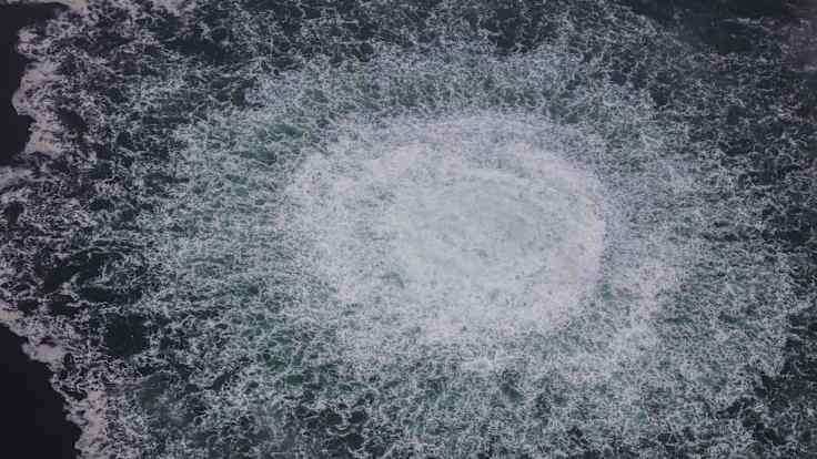 An aerial view of white foamy bubbles in dark blue water as gas escapes from a burst pipeline under the Baltic Sea.