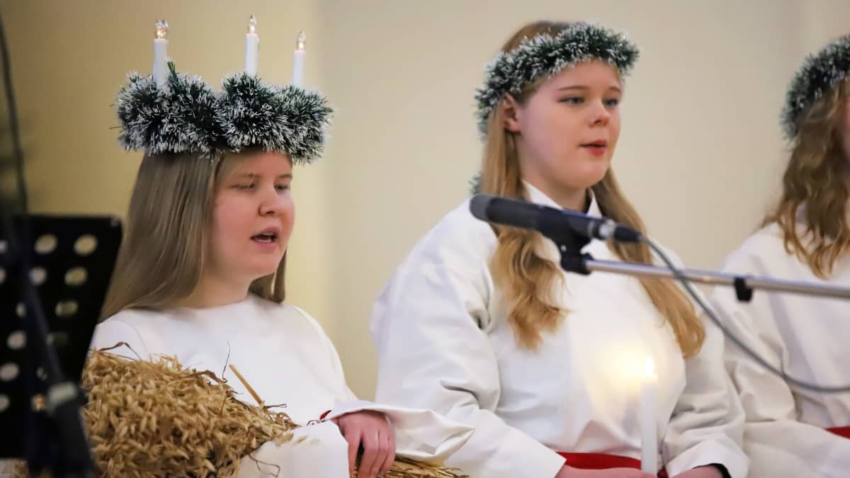 Mikkelin lukion Lucia-neito 2021 Mirella Snellman laulaa Mikkelin tuomiokirkossa, vieressä Lucia-kulkueeseen kuuluva Anna Läntinen.