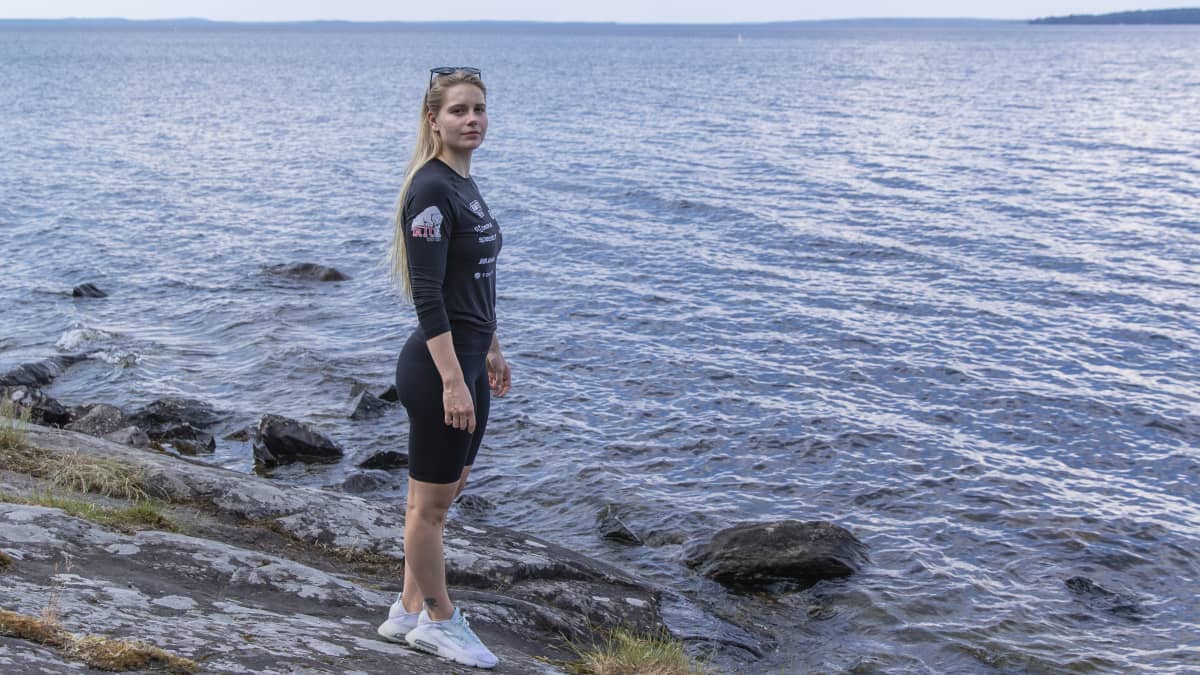 Ida Hulkko seisoo Näsijärven rantakalliolla. Taustalla kimaltelee järven pinta.