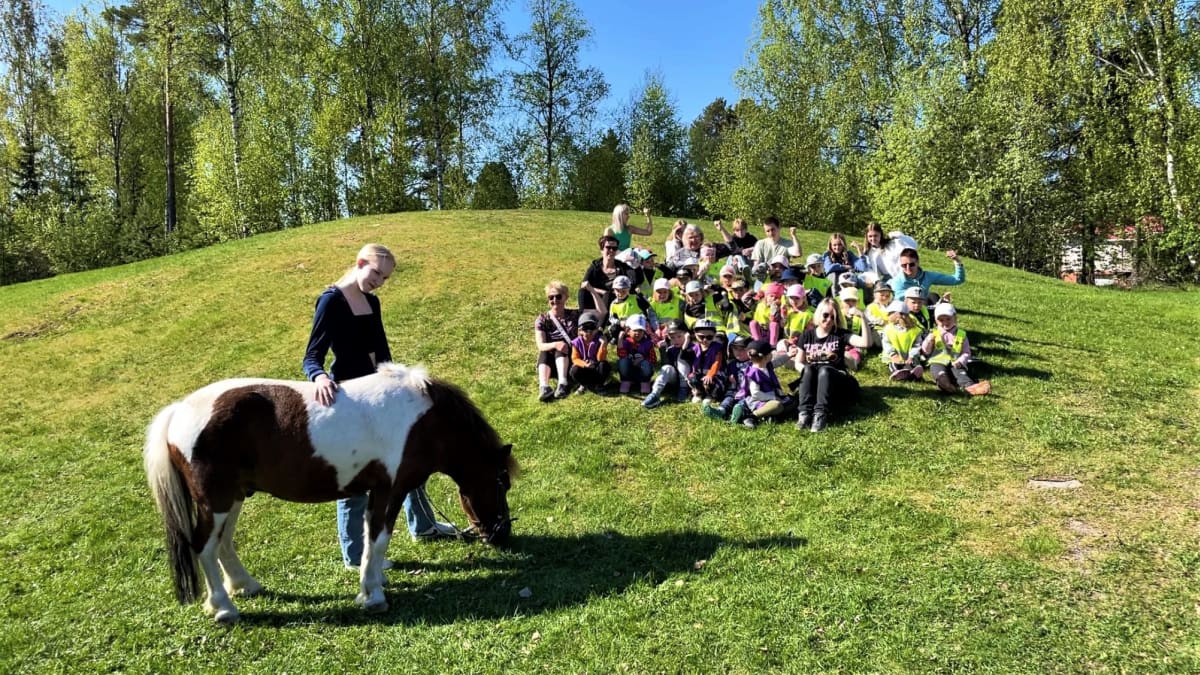 Lapset ja nuoret istuvat nurmikolla Metsäkallion päiväkodin pihalla Vaasassa, kuvan etualalla poni, joka tuli päiväkotiin vierailulle.