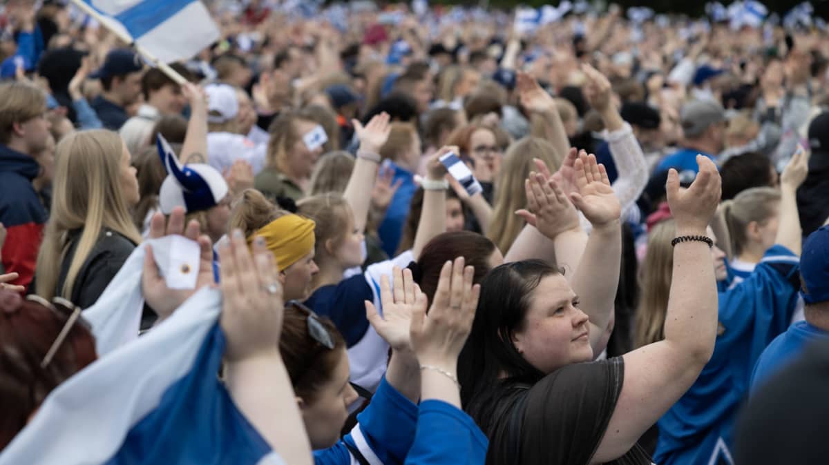 Ihmisiä taputtamassa kultajuhlayleisössä.