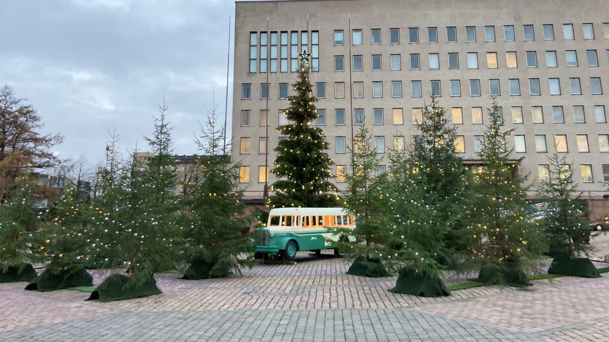 Leikkibussi valaistujen kuusien keskellä Kotkan Kauppatorilla. Taustalla on kaupungintalo.