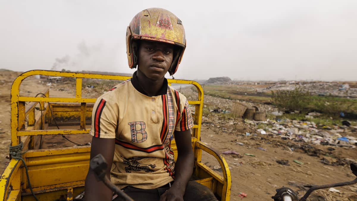 Nuori mies vaatteiden kaatopaikalla lähellä Ghanan pääkaupunkia Accraa.