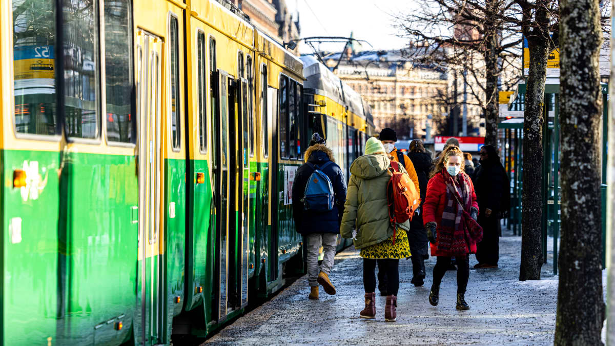 Ihmisiä raitiotiepysäkillä.