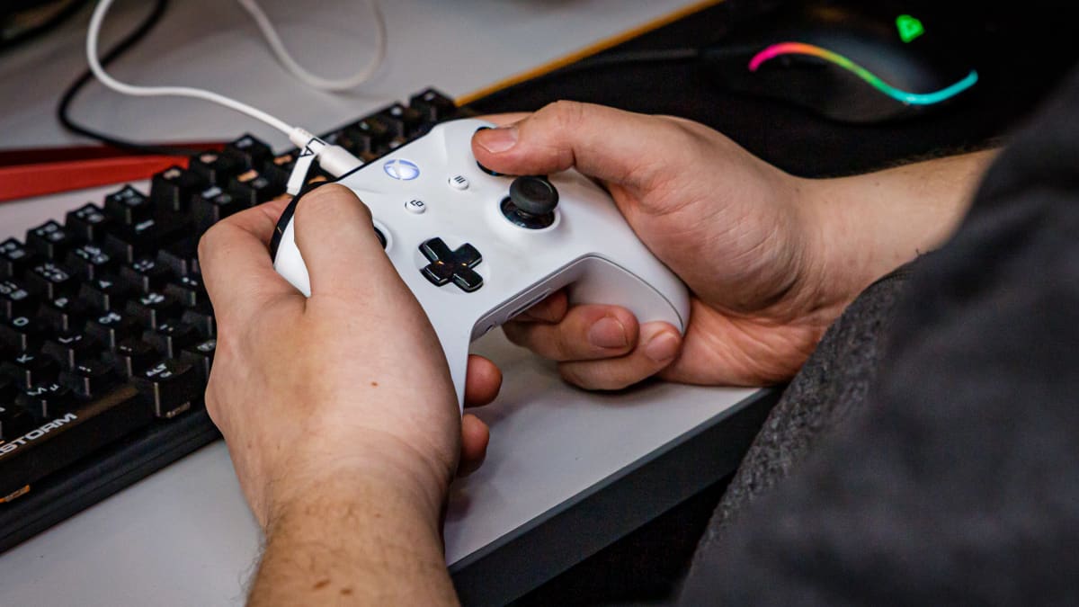 Miehen kädet valkoisella Xboxin peliohjaimella.