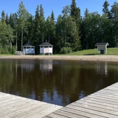 Takajärven uimaranta ja laituri kuvattuna kesällä.  Taustalla vehreä metsä. 