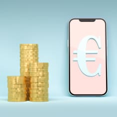 Euron kolikoita pinossa ja digitaalinen euro eli euron symboli matkapuhelimen näytöllä.