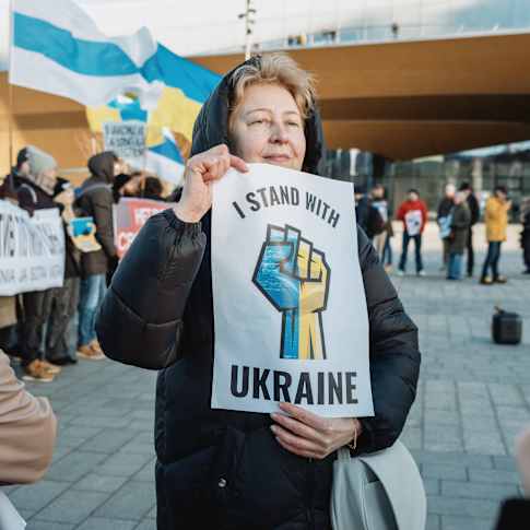 Ukrainan sodan vastaiseen mielenosoitukseen osallistuva nainen pitelee kylttiä, jossa lukee "I stand with Ukraine".