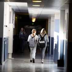 Two girls walking in a school hallway.