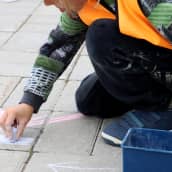 Lapsi piirtää liiduilla kivetykseen