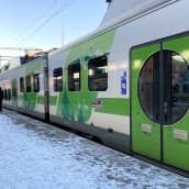 Lahden rautatieasemalla VR:n juna laiturilla pysähtyneenä, matkustajat kävelevät kohti junan sisäänkäyntejä. Talvi, lunta laiturilla.