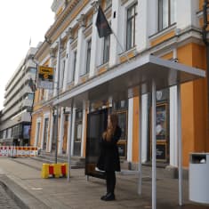 Kvinna framför busskur. 