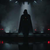 Darth Vaderin uhkaava, tumma siluetti erottuu vaaleaa savua vasten pimeässä huoneessa. Kuva on Obi-Wan Kenobi -sarjasta.