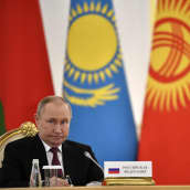 Venäjän presidentti Vladimir Putin kultaisessa tuolissa, taustalla Valko-Venäjän, Kazakstanin, Kirgisian ja Venäjän liput.