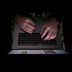 Miehen kädet kirjoittaa kannettavalla tietokoneella.