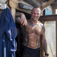 Runsaasti tatuoitu mies poseeraa saunan ovella Sompasaunalla Helsingissä.