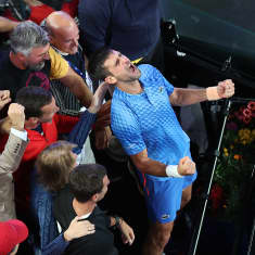 Novak Djokovic juhlii voittoaan tukijoukkojensa kanssa katsomossa. 