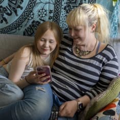 Tytär Vilma äitinsä Kiran kainalossa kodin sohvalla.