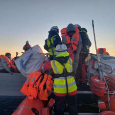 Henkilöitä pelastusliiveissä istuu veneessä.
