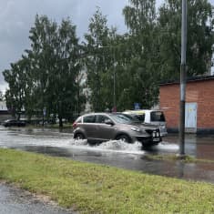 Autot liikkuvat kadulla, jolle tulvii vettä.