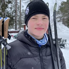 Poika sukset ja sauvat olallaan.