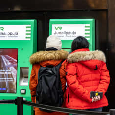 Photo shows two people buying tickets from a VR automatic machine.