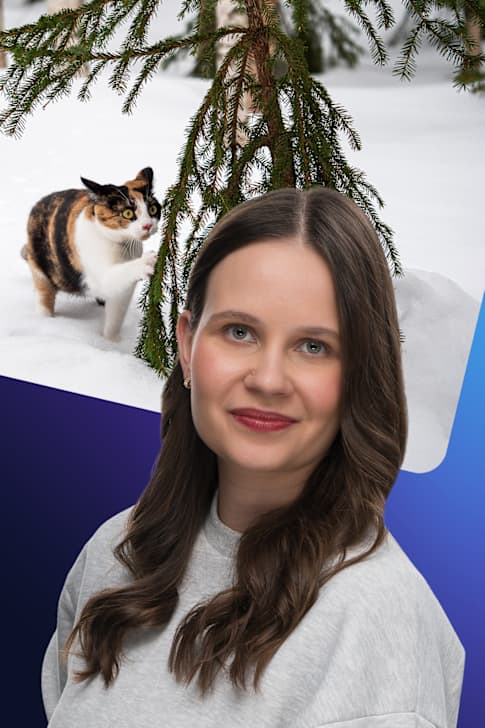 Laura Törnroos står framför en bild på en katt i snö som håller en tass mot en grankvist.